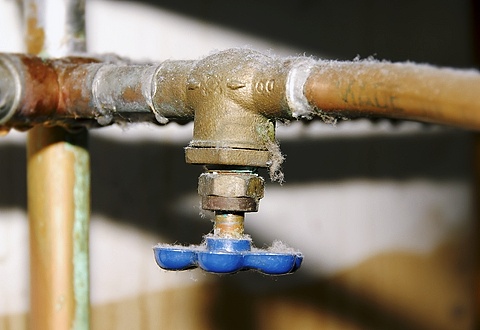 A close-up of an old metal water valve with a blue handle, showing signs of corrosion and buildup. Perfect for an emergency plumber in Atlanta to address any urgent plumbing needs.