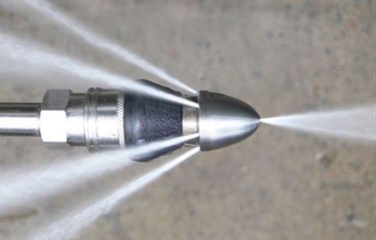 Close-up of a high-pressure water jet nozzle spraying water streams from several openings in different directions, expertly handled by an emergency plumber in Atlanta.