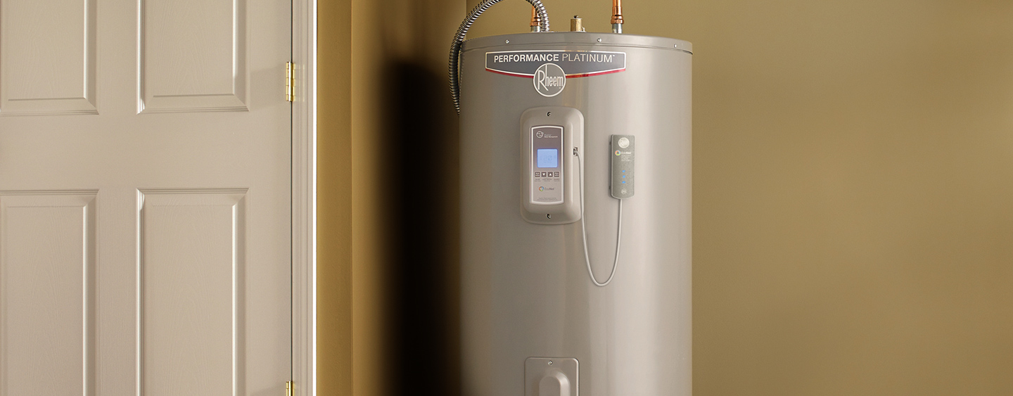 A gray Rheem Performance Platinum water heater is installed next to a closed door in a beige room, ready for a plumbing inspection.