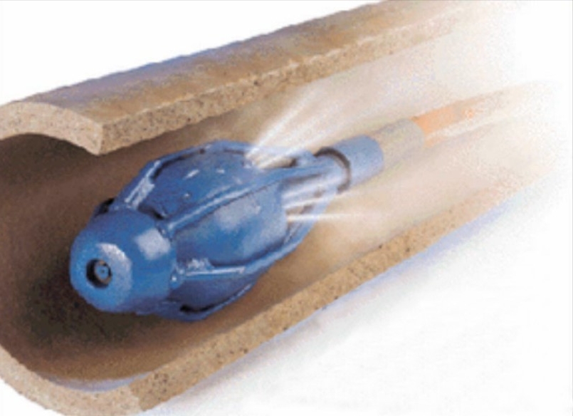 A blue pipe cleaning tool is shown inside a sectioned, brown pipe. The tool emits jets of water, indicating it is in operation, potentially addressing issues related to water heater repair or burst pipe repair.