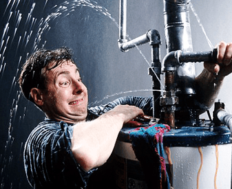 A man struggles to fix a leaking pipe on a water heater, with water spraying out in multiple directions. Emergency plumber in Atlanta or 24/7 plumbing service would be essential for a burst pipe repair.