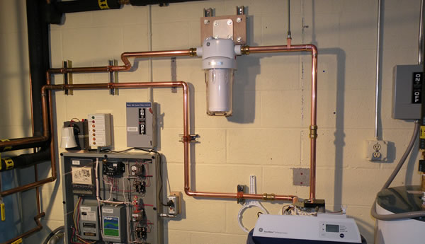 The image shows a water filtration and control system installed on a wall with copper pipes, a filtration unit, and electronic control panels, ideal for those seeking water heater repair or emergency plumber services in Atlanta.